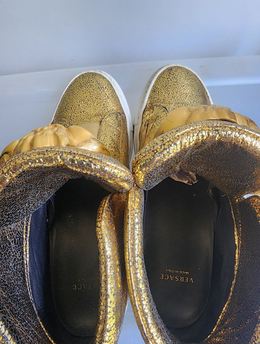 The metallic gold Versace sneakers is like new .